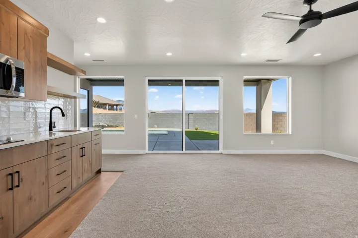 Open-concept living space featuring wood-finish cabinetry, a large sliding glass door, recessed lighting, and a ceiling fan