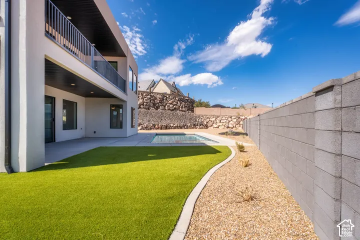 Modern exterior with an upper-level balcony featuring metal railings, a concrete patio, and a swimming pool