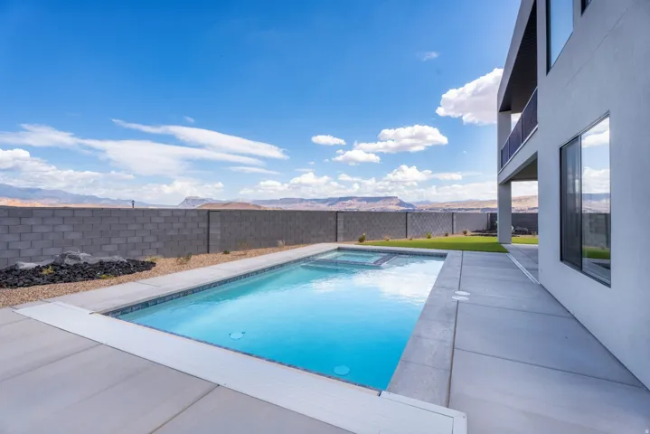 Rectangular inground pool with integrated spa, concrete patio surround, and an integrated pool cover