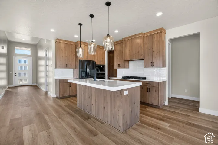 Gourmet kitchen with wood-finish cabinetry, white countertops, and subway tile backsplash