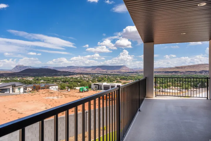 Covered outdoor balcony with a black metal railing, offering expansive desert and mountain scenery