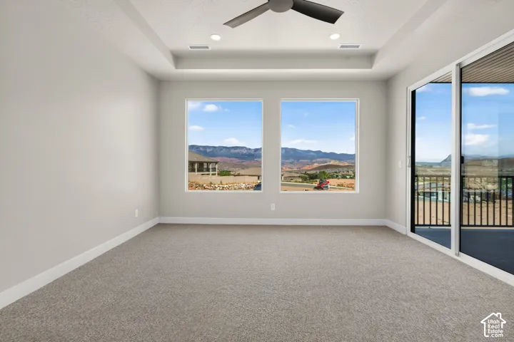 Recessed lighting, ceiling fan, tray ceiling, sliding glass door, and two large windows