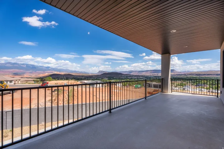 Expansive covered balcony featuring a durable concrete surface and a sleek black metal railing