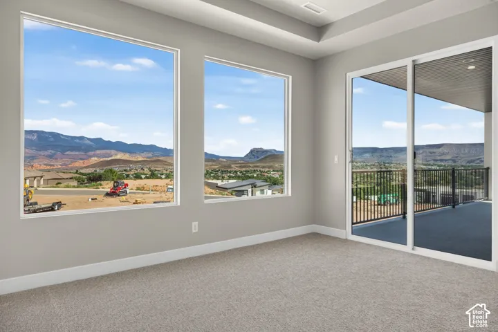 Recessed lighting, tray ceiling, sliding glass door to a balcony, large windows, and neutral carpeting
