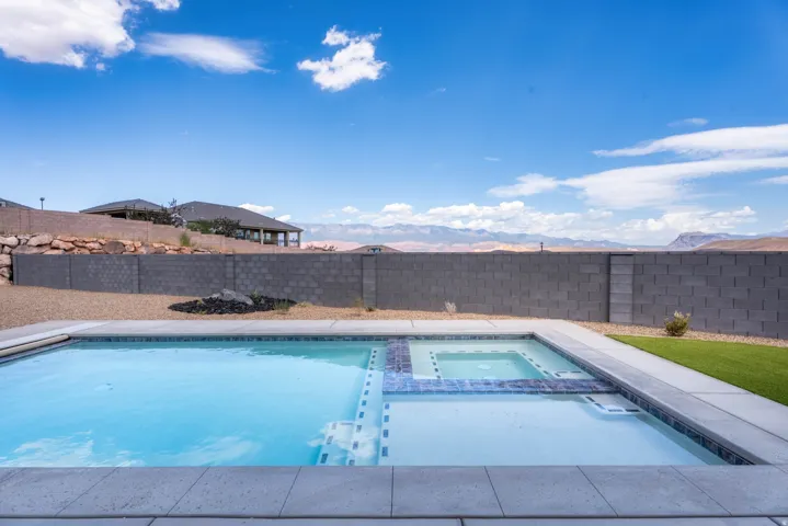 In-ground swimming pool with integrated spa, concrete coping, and decorative tile accents