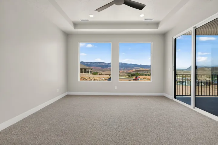 Recessed lighting, ceiling fan, tray ceiling, sliding glass door, and two large windows