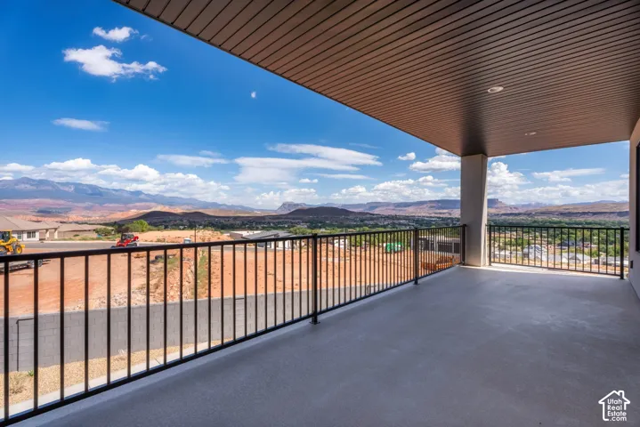 Expansive covered balcony featuring a durable concrete surface and a sleek black metal railing