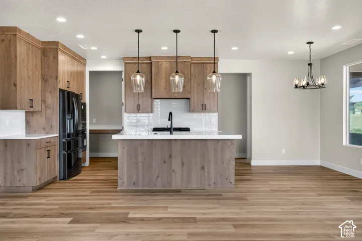 Wood-finish flooring throughout, kitchen island with pendant lighting, built-in cabinetry, white tile backsplash, and recessed lighting