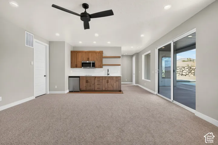 Built-in wet bar with wood-finish cabinetry, stainless steel sink, and open shelving