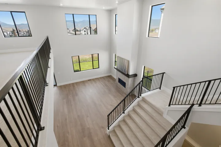 Two-story living area with high ceilings, large windows, recessed lighting, a fireplace with a stone surround