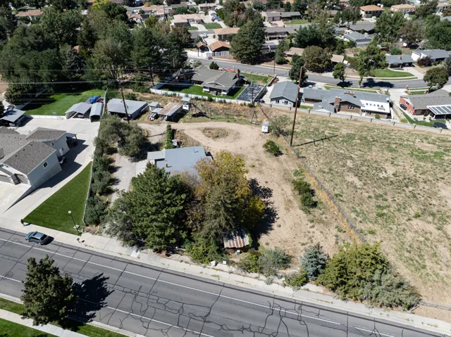 Expansive parcel featuring a main road frontage, mature trees, and existing structures