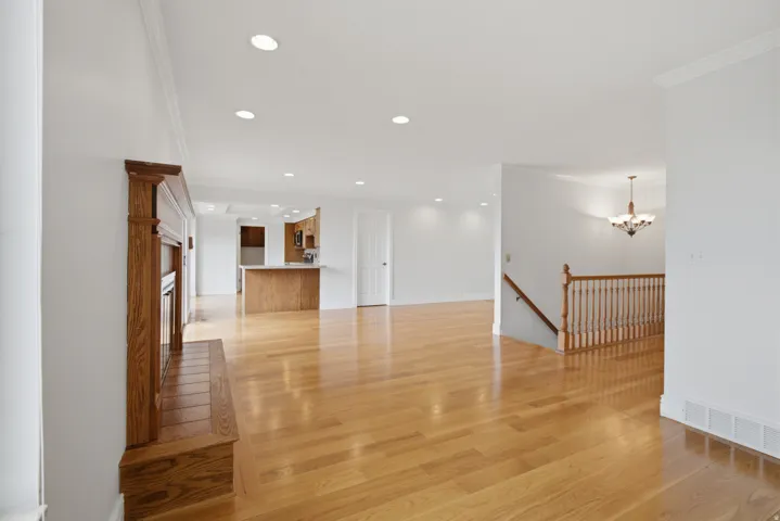 Hardwood flooring throughout, recessed lighting, and a wood-finish fireplace with tiled hearth