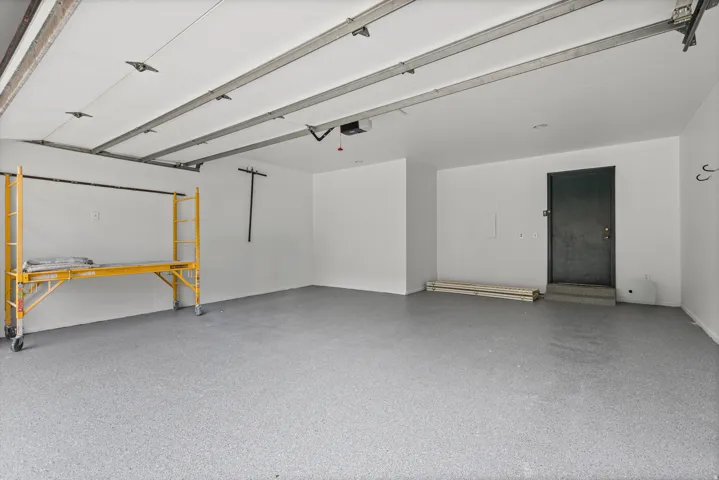 Spacious garage featuring a durable epoxy floor finish, white painted walls, and an overhead door system