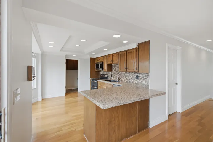 Kitchen with wood cabinetry, stainless steel appliances, and a tiled backsplash