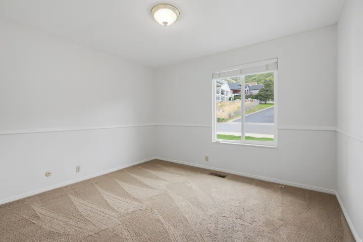Bright interior with neutral carpeting, white walls, a single window, and flush-mount ceiling lighting