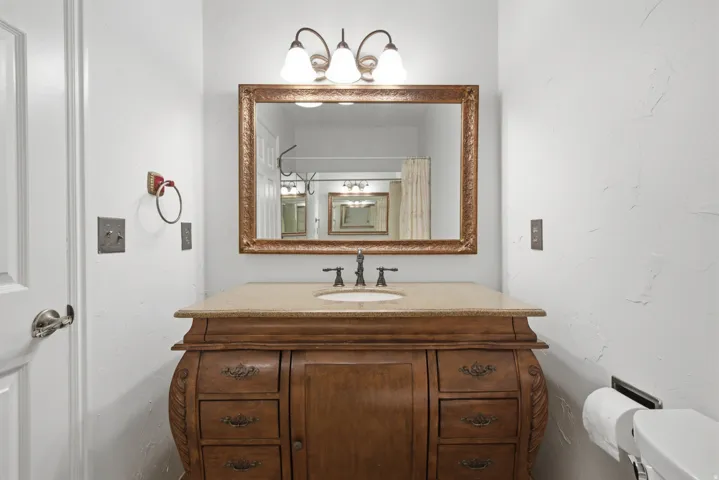Vanity with a granite countertop and an undermount sink, framed mirror, and three-light fixture