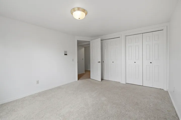 Wall-to-wall carpeting, two bi-fold panel doors, single panel door, recessed ceiling light fixture, and light-colored walls
