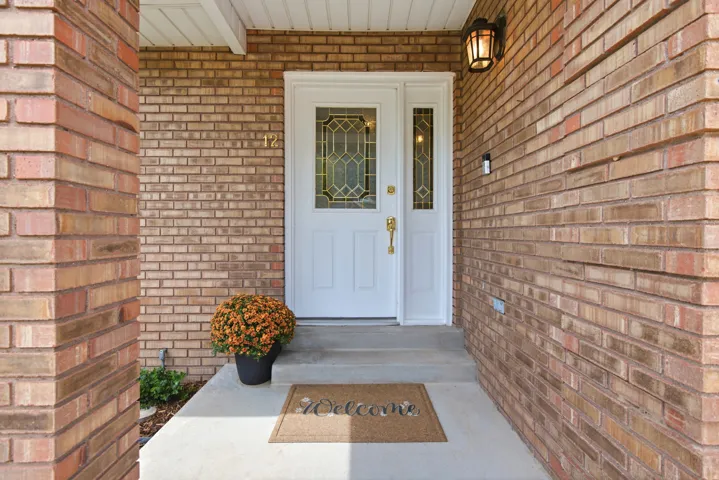 Brick exterior with a white entry door, decorative sidelight, and a matching door frame
