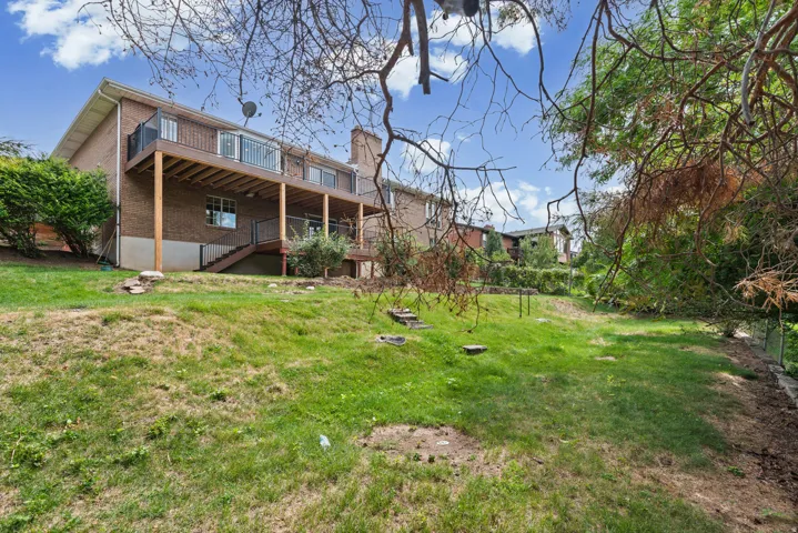 Brick exterior with a multi-level deck, dark wood-finish railing, and a walk-out basement