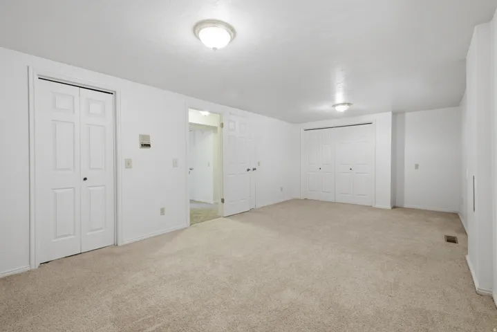 Neutral tone wall paint, carpeted flooring, two sets of bi-fold closet doors, and recessed ceiling lighting