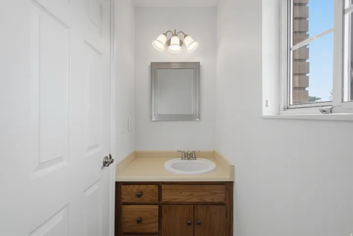Vanity with an integrated sink, a large mirror, and a wall-mounted light fixture