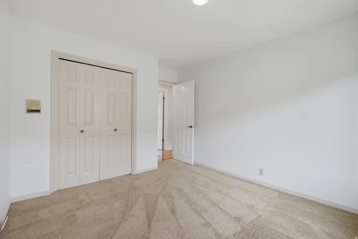 Neutral-toned carpeting, white walls, and a recessed ceiling light