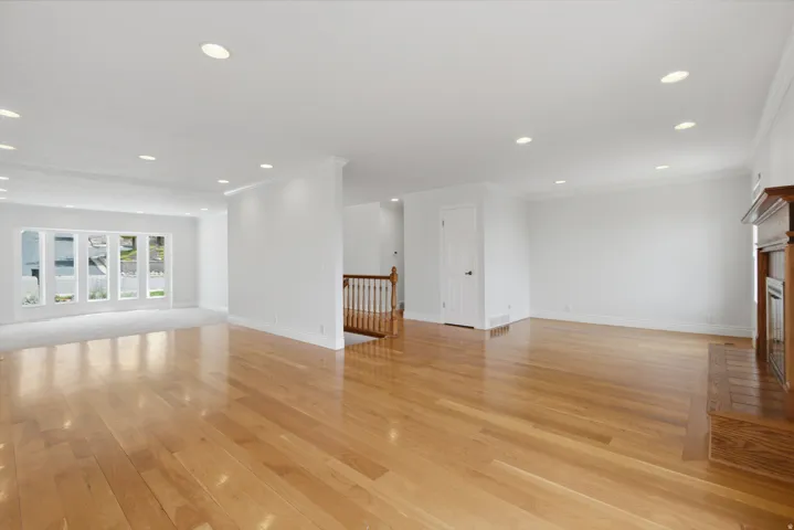 Hardwood flooring throughout, recessed lighting, white trim, and a fireplace with a wood mantle