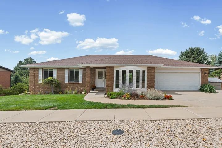 Brick exterior, bay window, attached garage, concrete driveway, and established landscaping