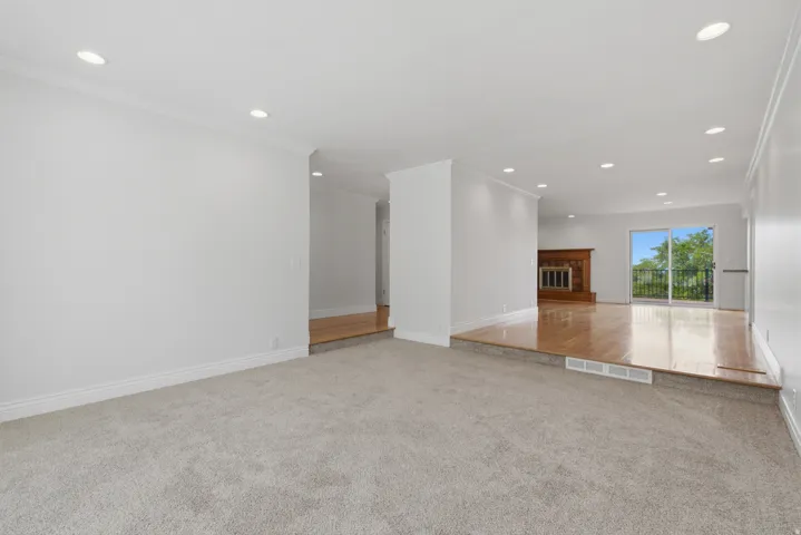 Sunken living area with hardwood flooring, fireplace, and sliding glass door to a balcony