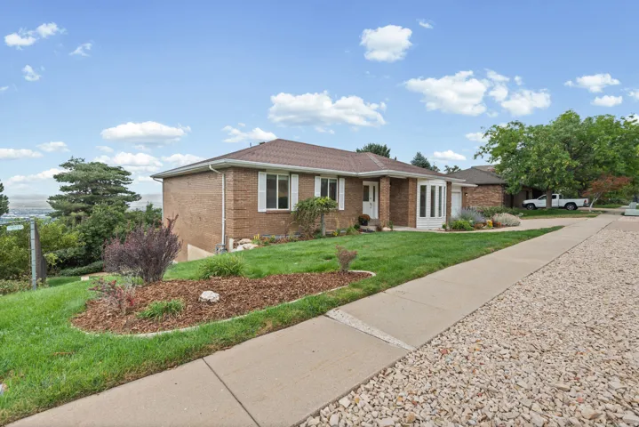 Brick exterior with white trim, a covered entry, and a mature landscaped yard