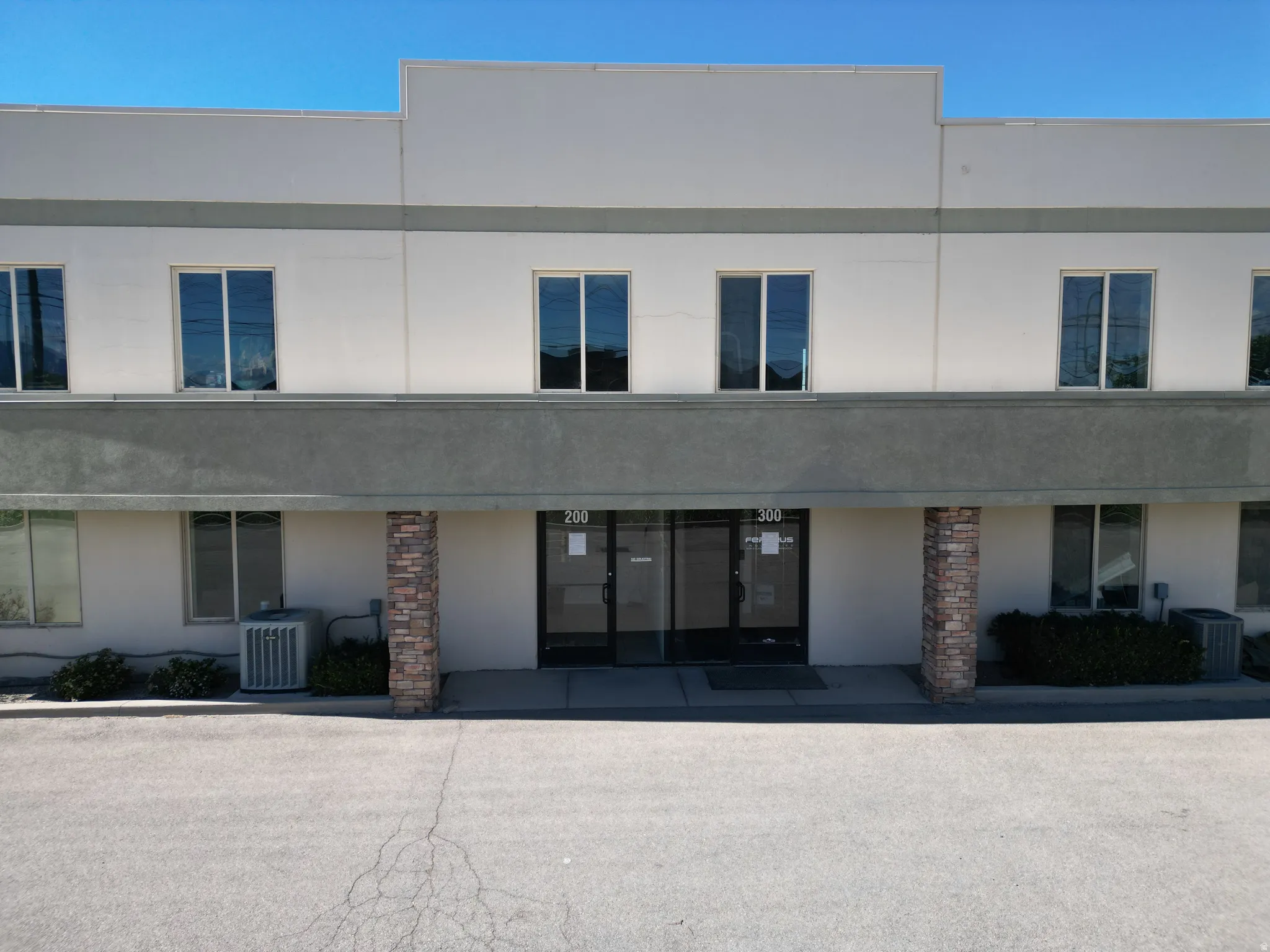 Two-story commercial building featuring a stucco exterior with stone-clad columns, multiple windows, and two distinct entrances with transom windows