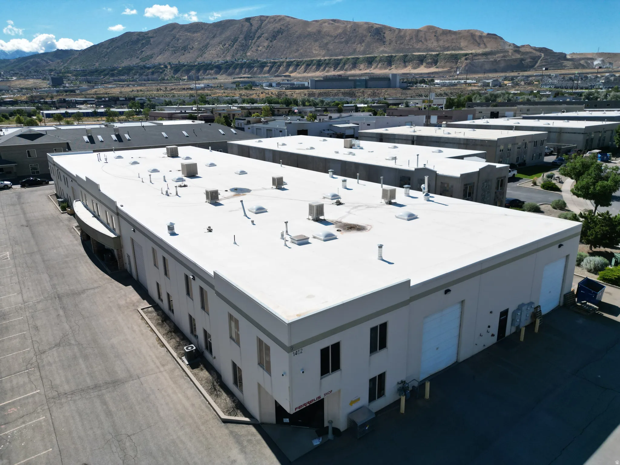 Large commercial building with multiple roll-up doors, extensive parking area, and a flat roof