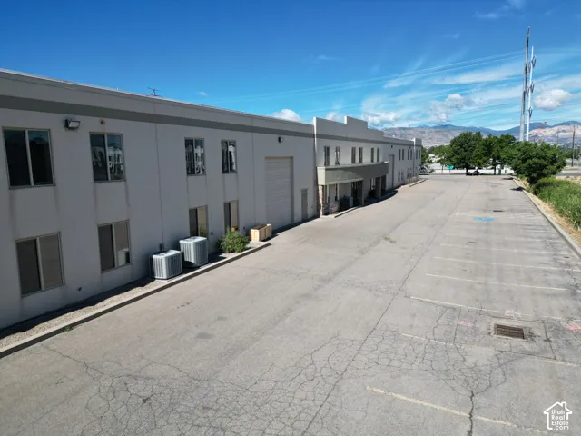 Expansive paved parking area, two-story commercial building, multiple windows, large garage door, and visible HVAC units