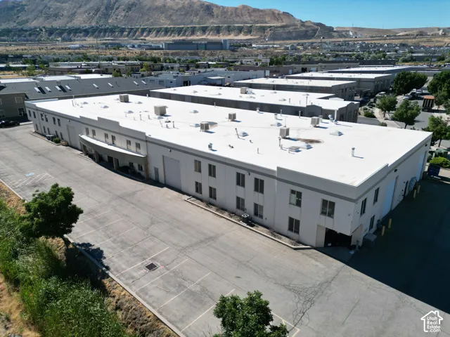 Large commercial building featuring multiple windows, several loading bay doors, a paved parking area, and a flat roofline