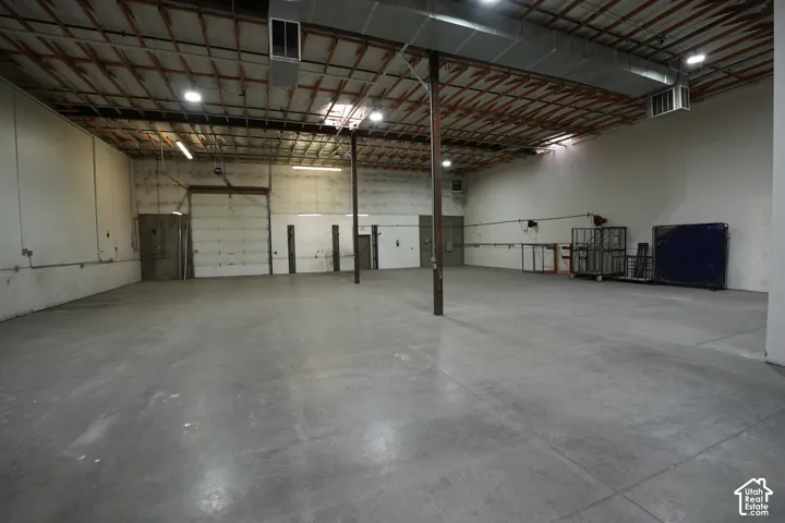 Expansive open warehouse space with concrete flooring, exposed ceiling joists, and overhead ductwork
