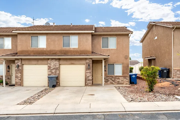 Stucco exterior with brick accents, two-car garage, and concrete driveway