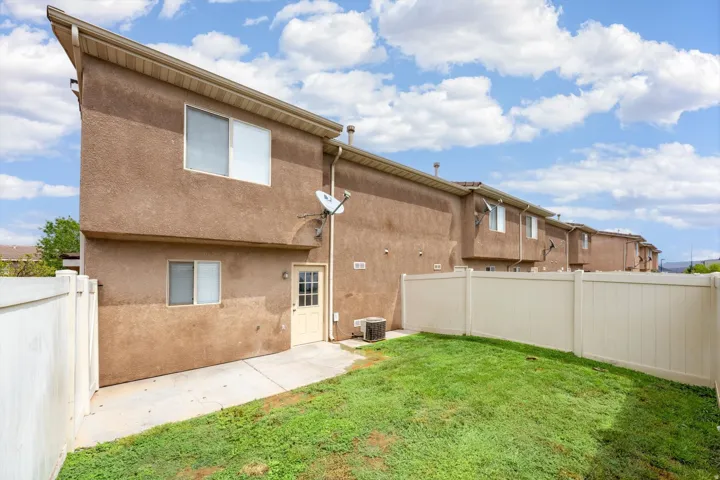 Private exterior space featuring a stucco finish, a sloped roofline, a rear entry door, and a vinyl privacy fence