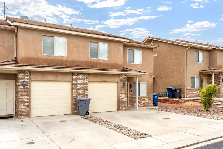 Stucco exterior with brick accents, two garage doors, and a covered entry