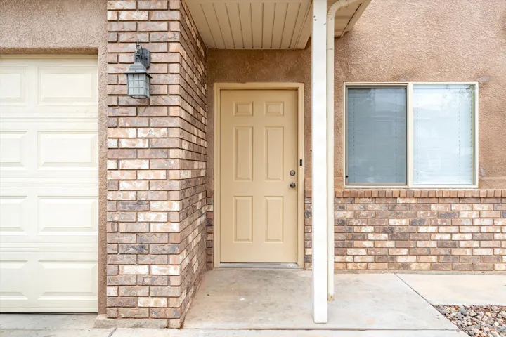 Brick and stucco exterior with a paneled garage door and an accent outdoor light fixture
