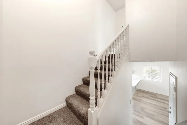 Carpeted staircase with white balusters and newel posts