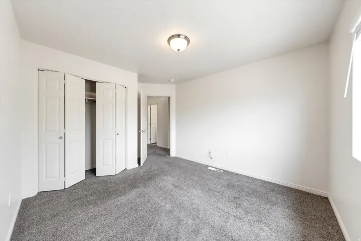 Wall-to-wall carpeting, bi-fold closet doors, and neutral wall tones