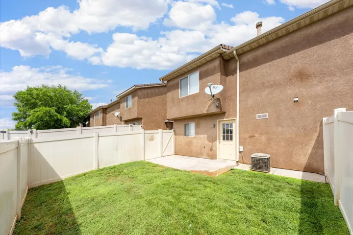 Private backyard featuring a fenced perimeter, green lawn, and concrete patio