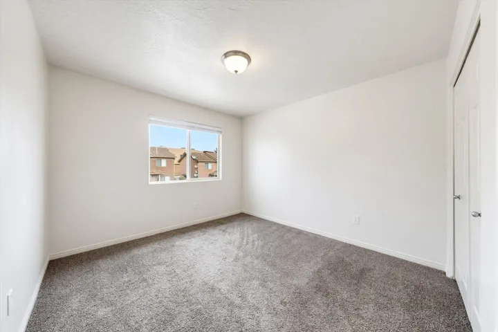 Neutral wall tones, gray carpeting, a single window, and a built-in ceiling light fixture