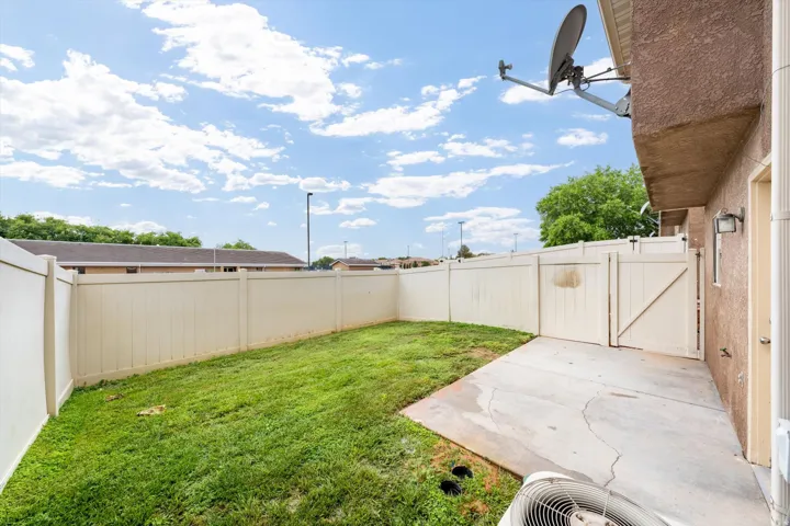Fenced yard featuring a concrete patio, a grass area, and a privacy fence with gate