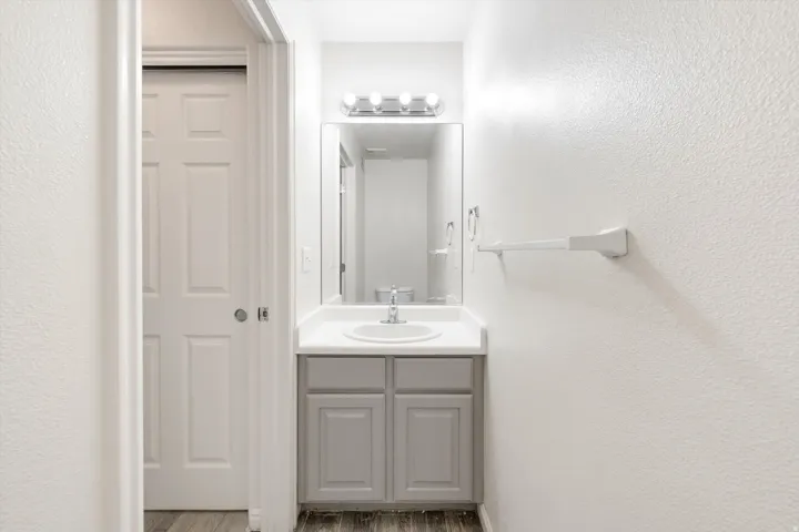 Vanity with gray cabinetry, an integrated sink, and white countertop