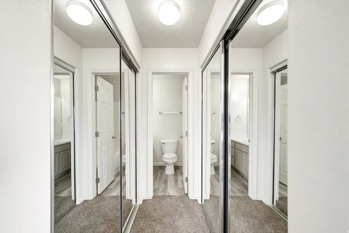 Mirrored sliding closet doors with track lighting, complementing a neutral color palette