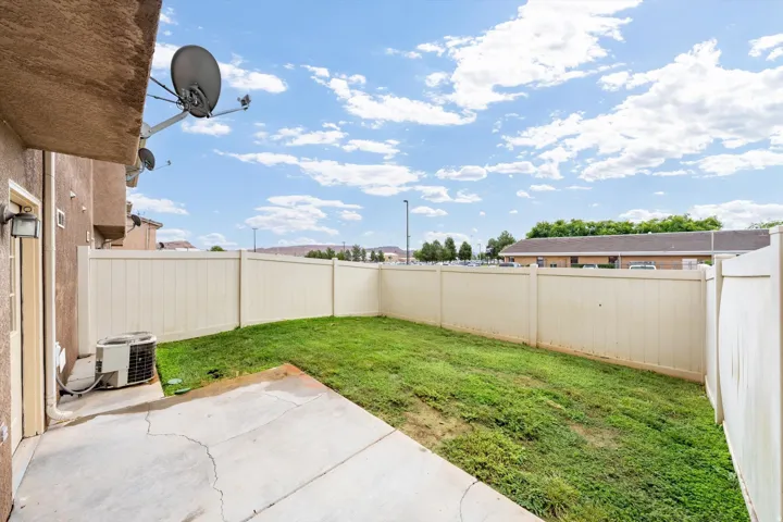 Private backyard featuring a concrete patio, grassy area, and perimeter fencing