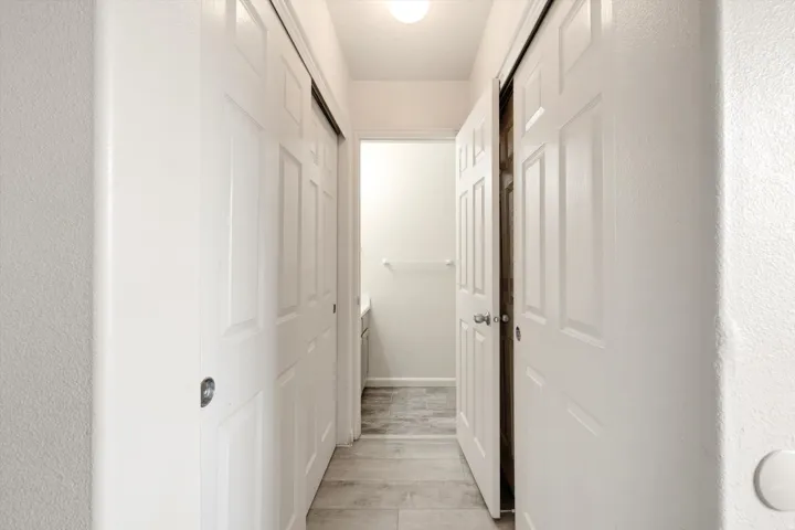 Hallway featuring paneled doors, sliding closet doors, and light gray tile flooring