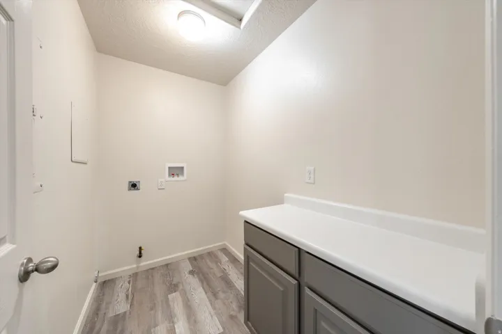 Wood-finish flooring, white walls, and a built-in counter with gray cabinetry