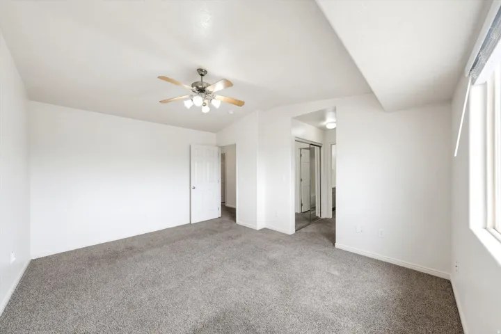 Angled ceiling with a ceiling fan, light gray carpeting, and a white door frame